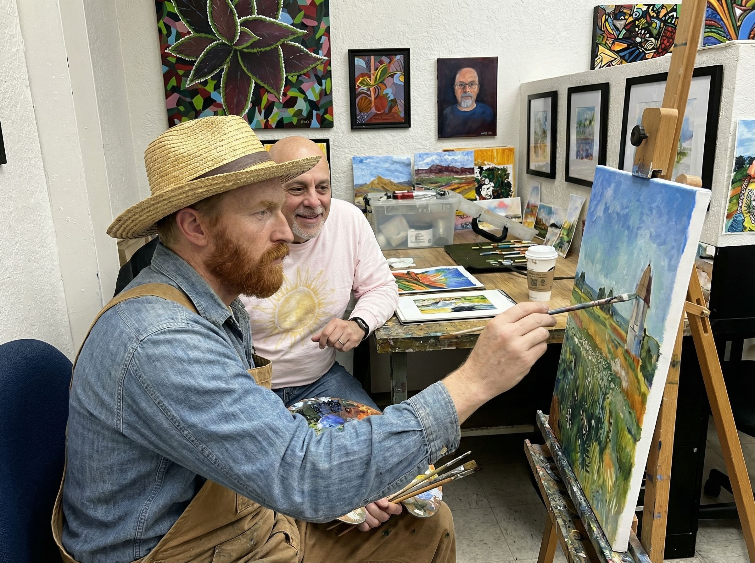 Craig Galati in an art studio beside an artist painting at an easel